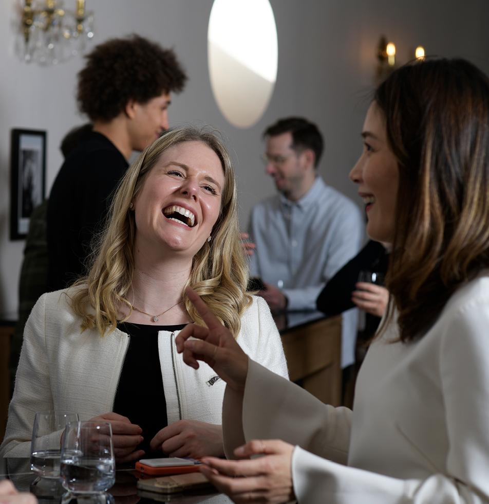 Woman laughing whilst the other speaks 