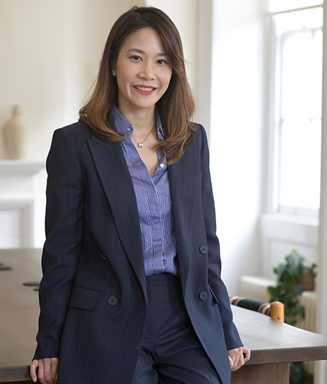 Asian woman leaning at a table smiling at the camera