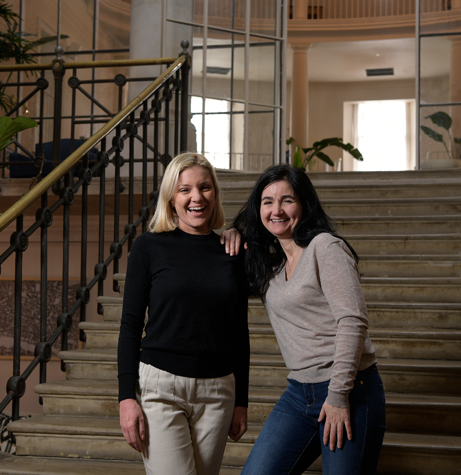 Two women smiling while standing at a staircase