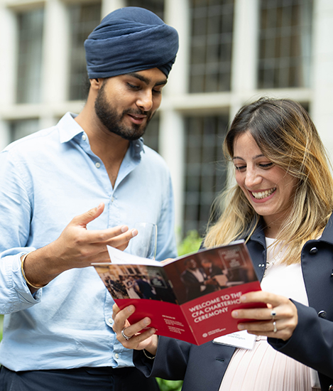 A man and woman smiling while holding a flyer