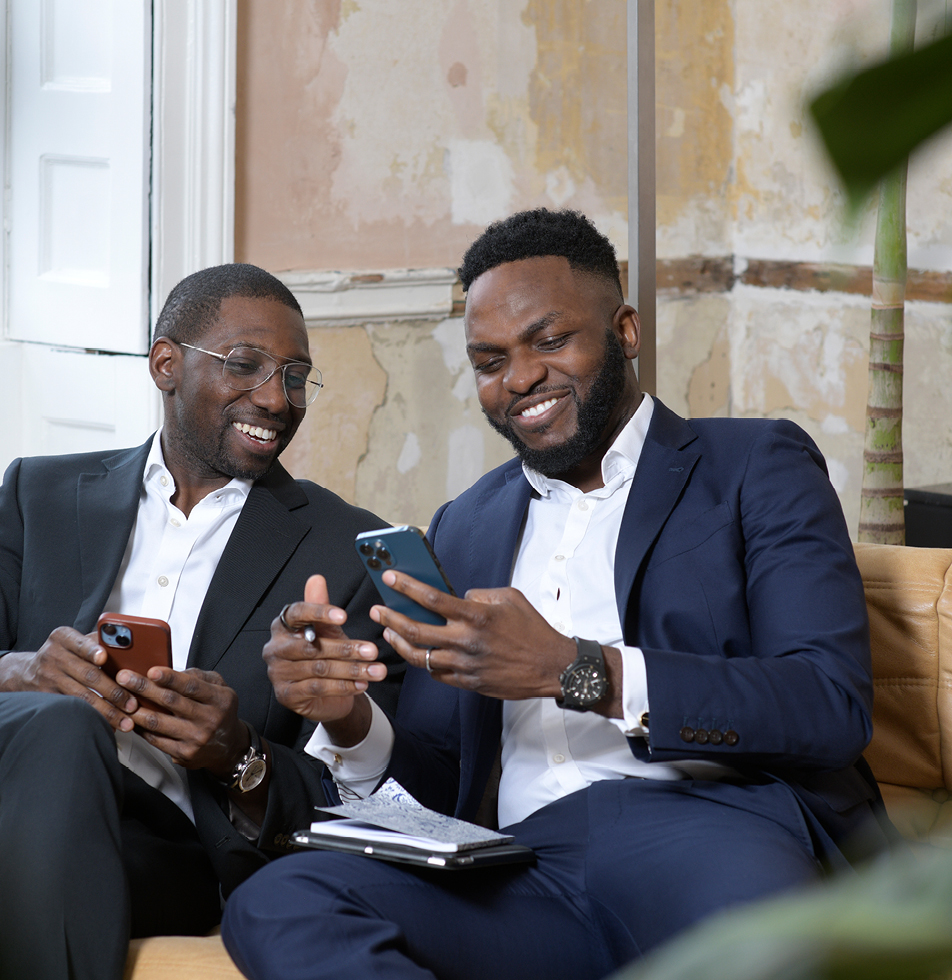 Two men looking at phones and smiling