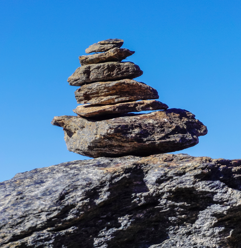 Blue sky with stones piled up on a large rock